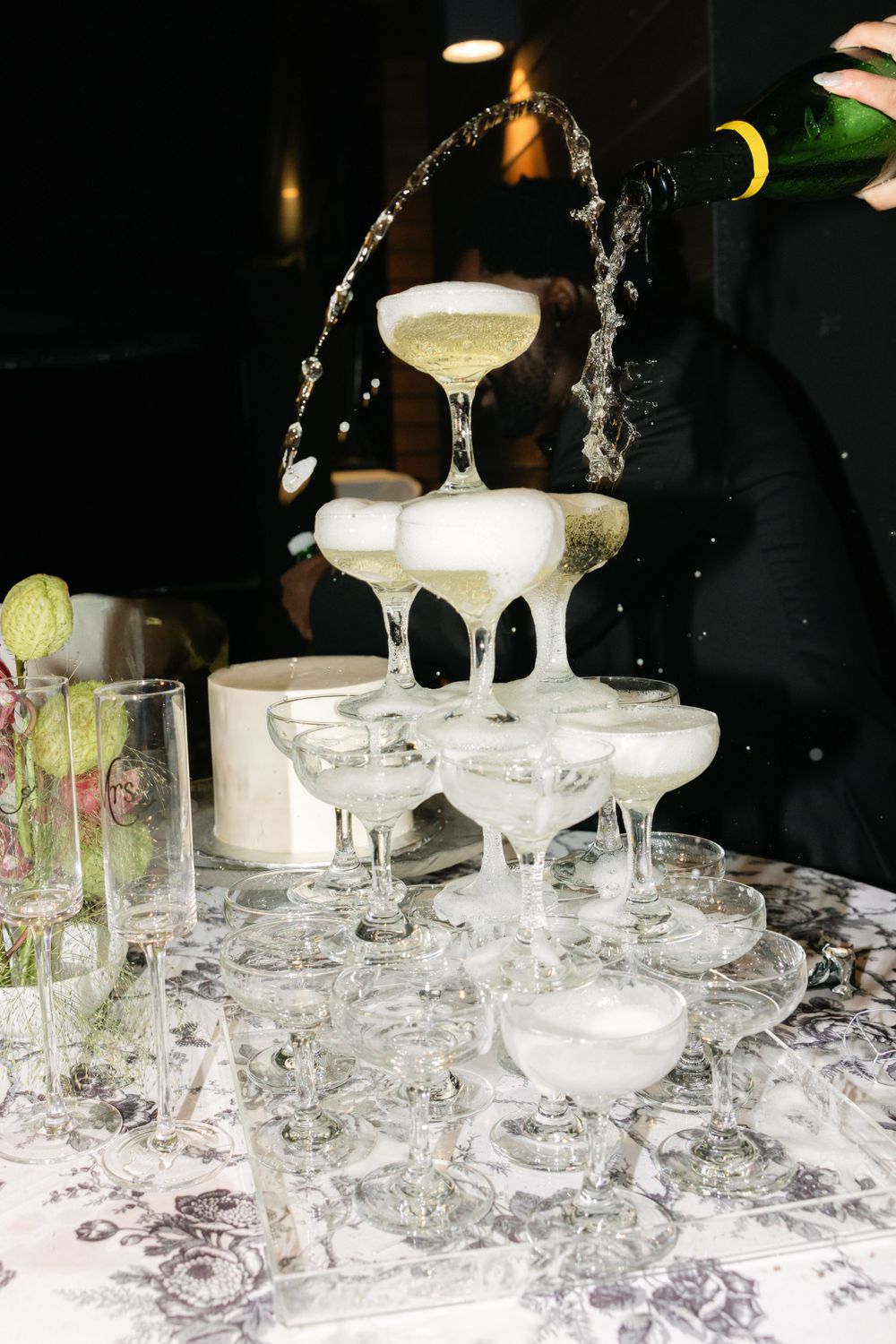 Champagne tower with liquid being poured creating a dramatic waterfall effect at an elegant party.