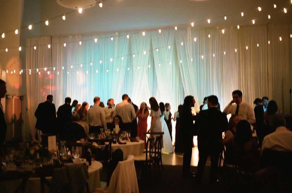 String lights create a romantic ambiance across a wedding reception venue ceiling.