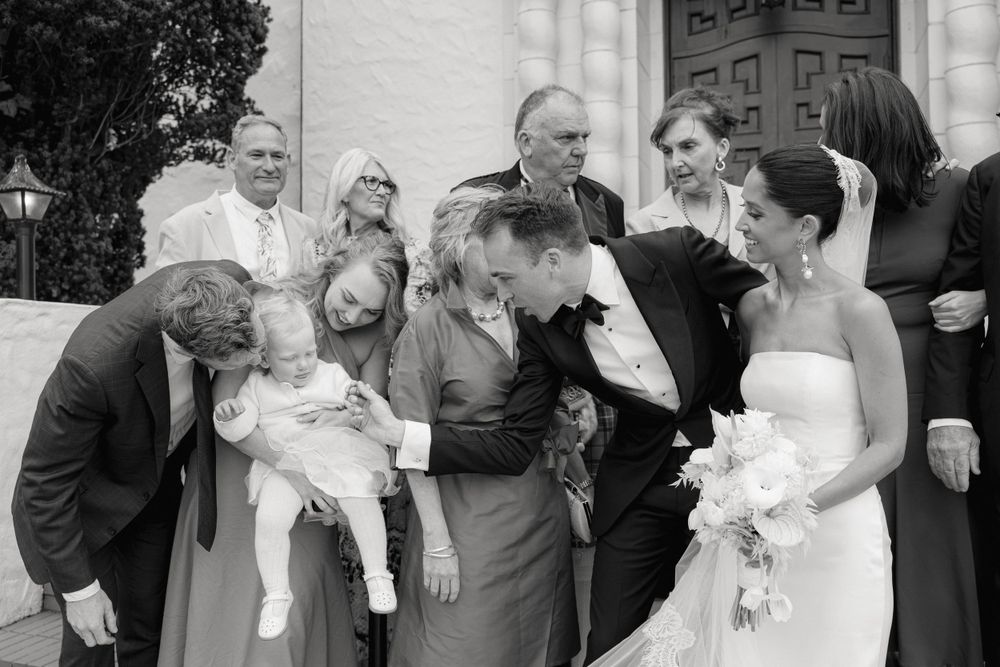 Candid black and white photo of wedding party members sharing a joyful moment together.