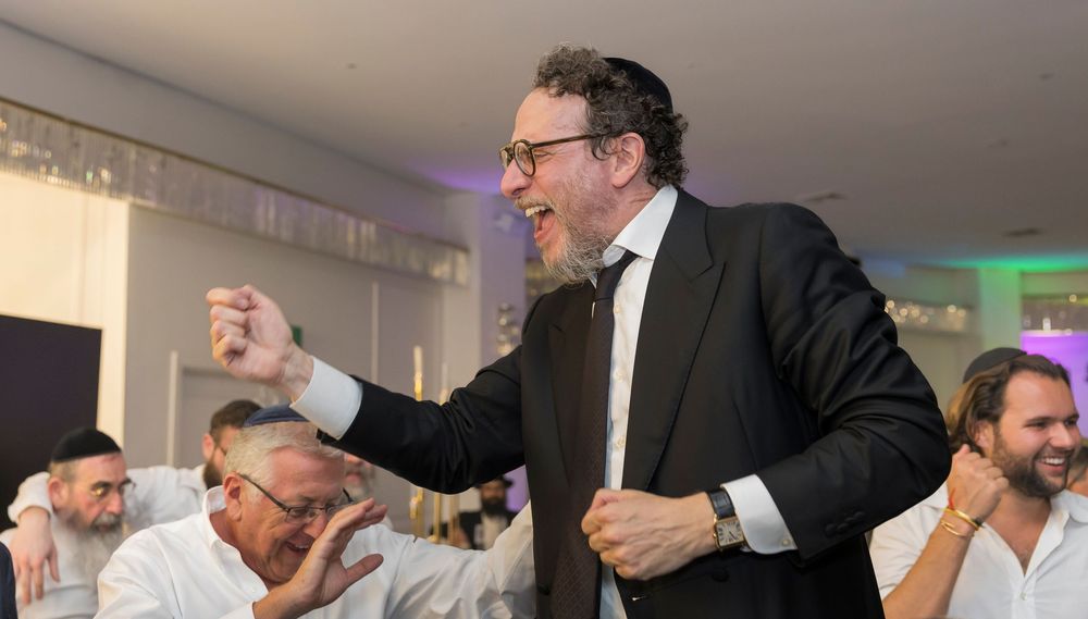 Professional speaker gestures energetically while presenting to an engaged business audience at a corporate event.