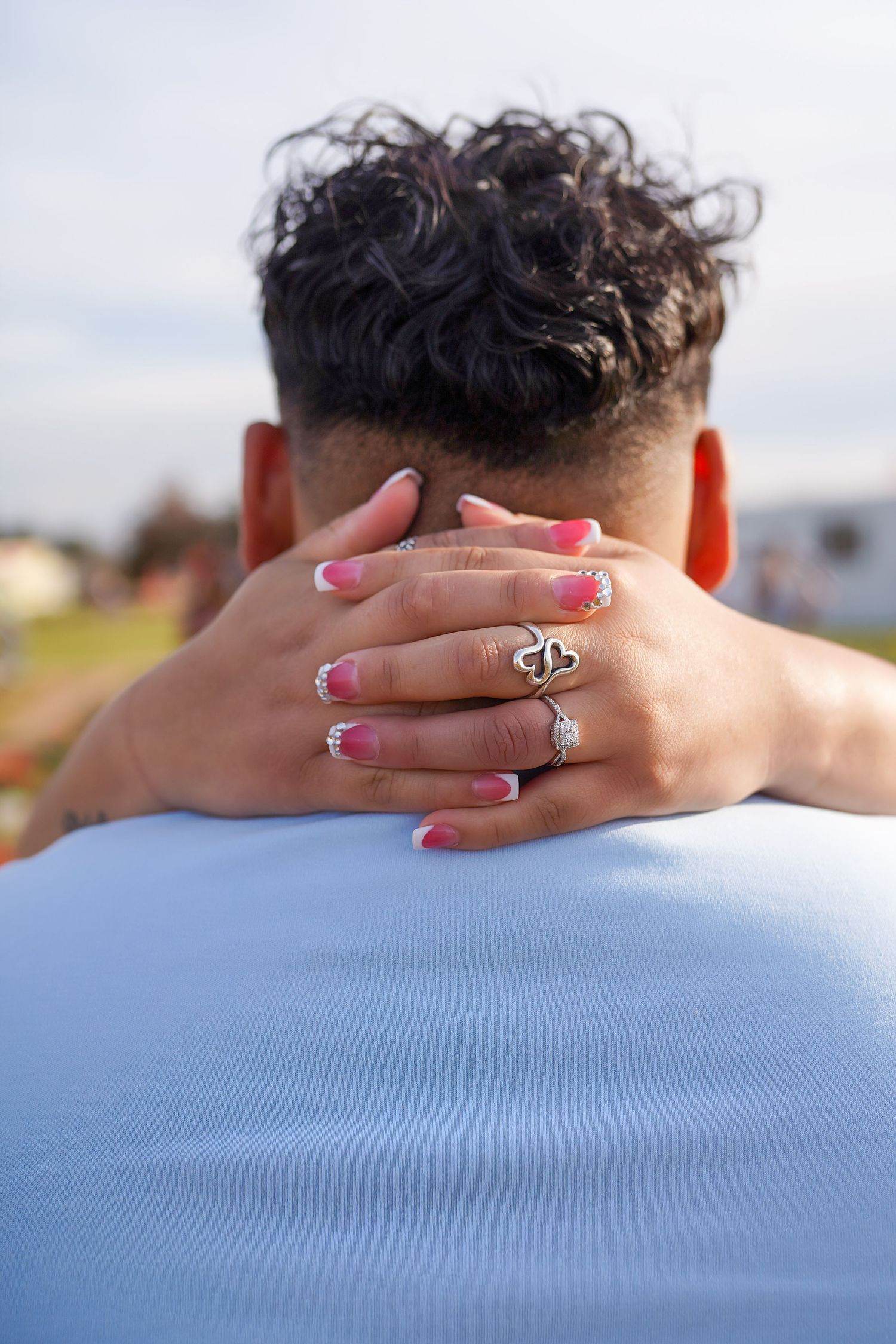 newly engaged couple in an embrace, with fiancee's painted nails and ring on display