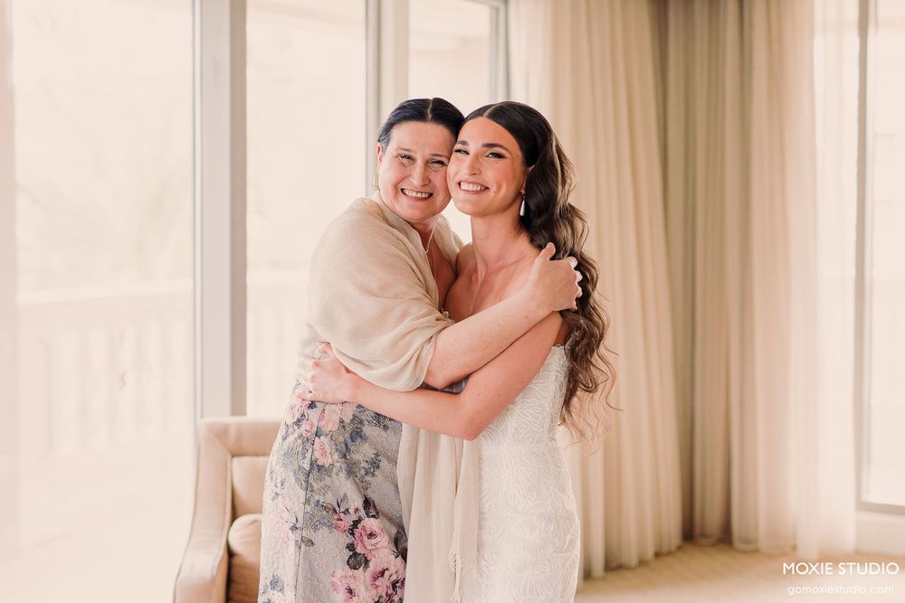 A romantic moment captured in a bright interior setting with soft curtains and natural lighting.