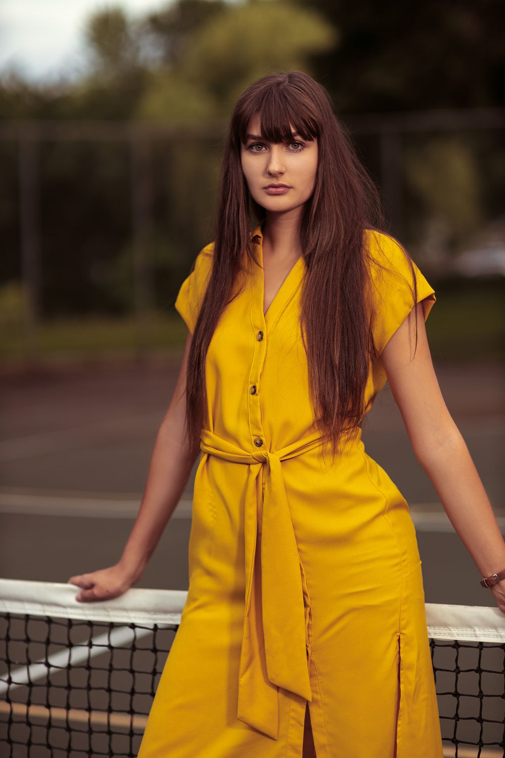 a beautiful female model wearing a yellow dress posing on a tennis net in Richfield, mn