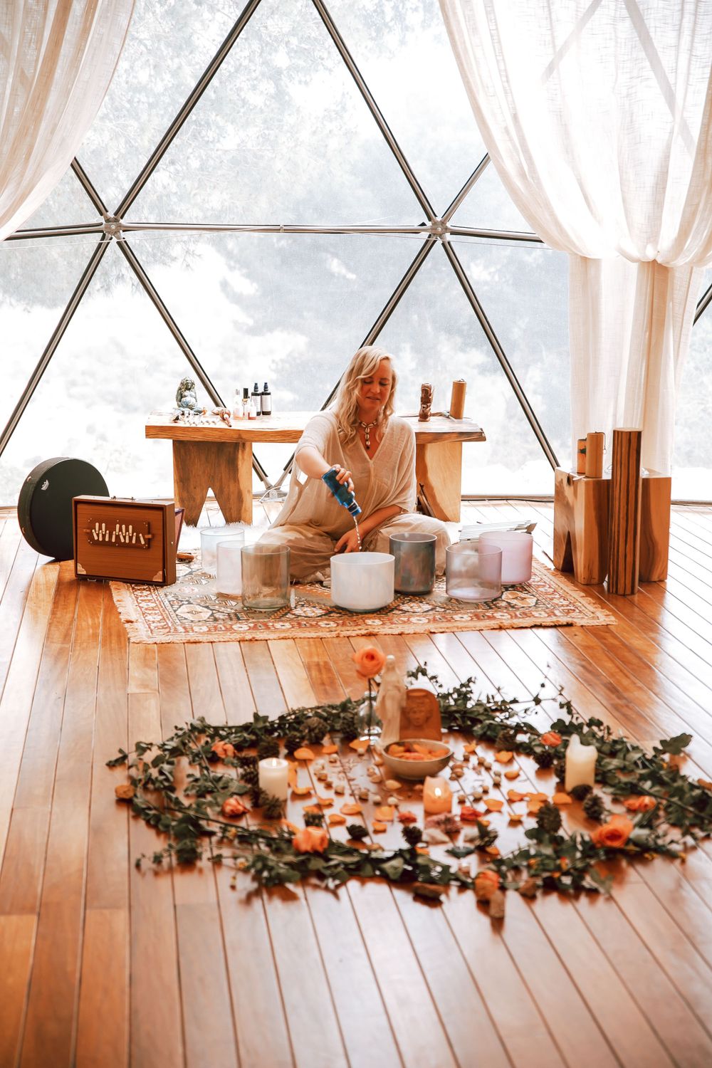 Geometric dome room with white curtains and wooden floor decorated with floral arrangements and candles.