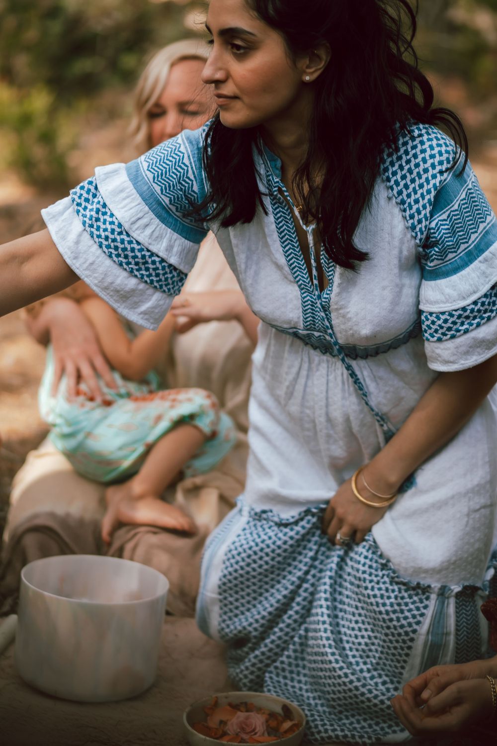 Person in vintage dress preparing food in rustic outdoor setting.