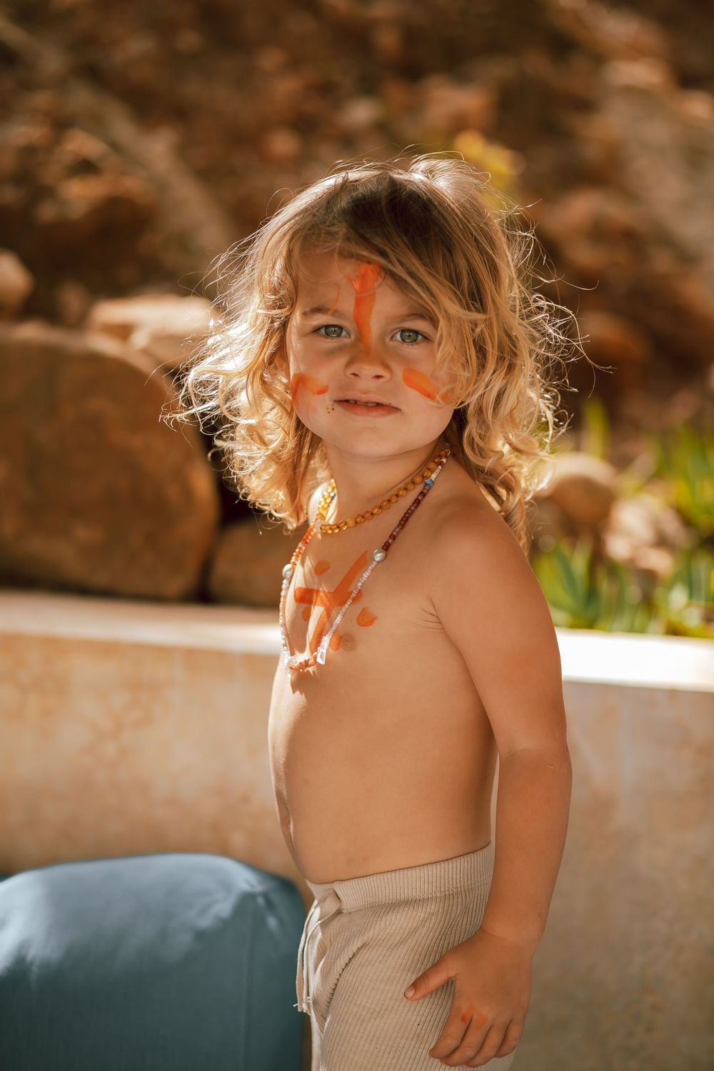 Child wearing beige top in natural sunlight outdoors.
