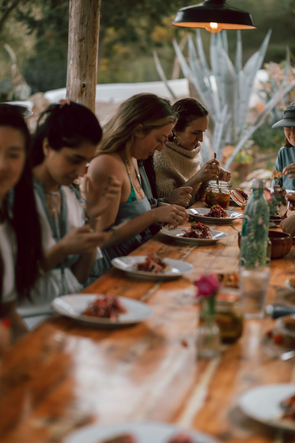 Group dining at a long wooden table with plates of food and drinks.