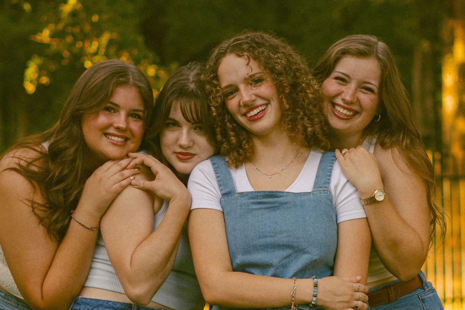 Four friends share joyful laughter together in warm sunset lighting.