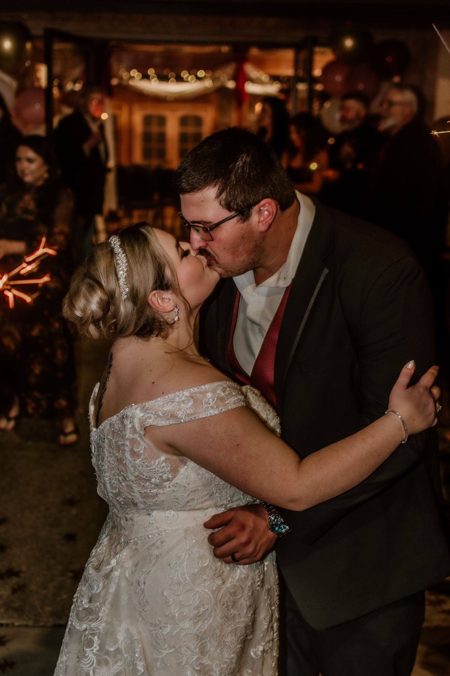 A couple dances together during their wedding reception in a dimly lit venue.
