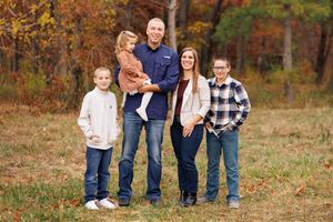 Family of 5 poses on their grandmother's property with a lovely fall background.