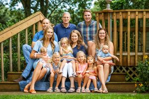 Large family posed on the deck stairs during a warm summer day.