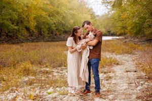 A new family of three standing in a dry creek bed during the fall season.