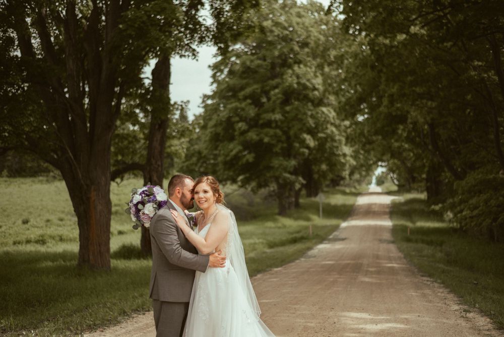 A joyful wedding moment captured on a tree-lined country road.