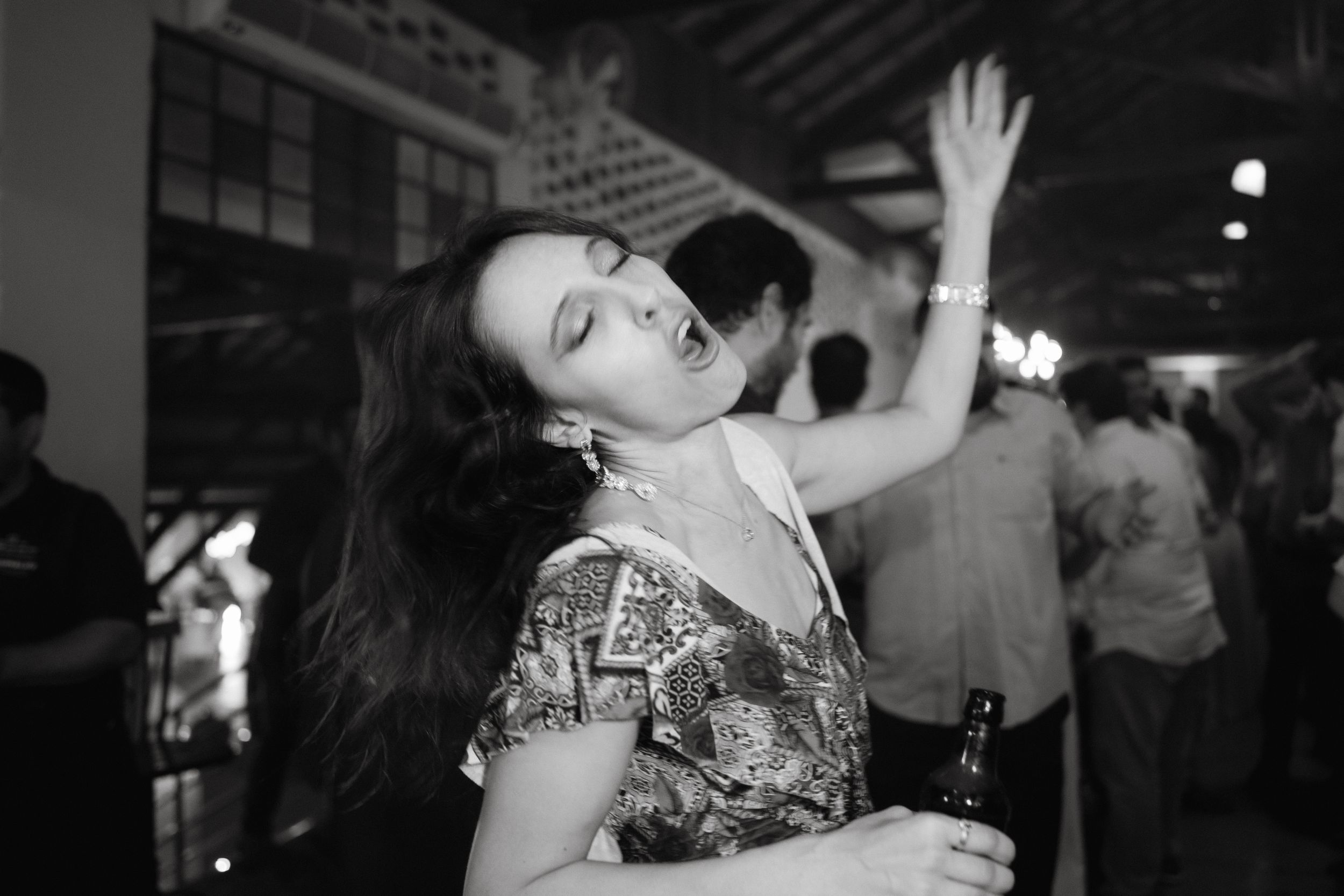 Black and white portrait of a wedding guest dancing expressively at a reception.