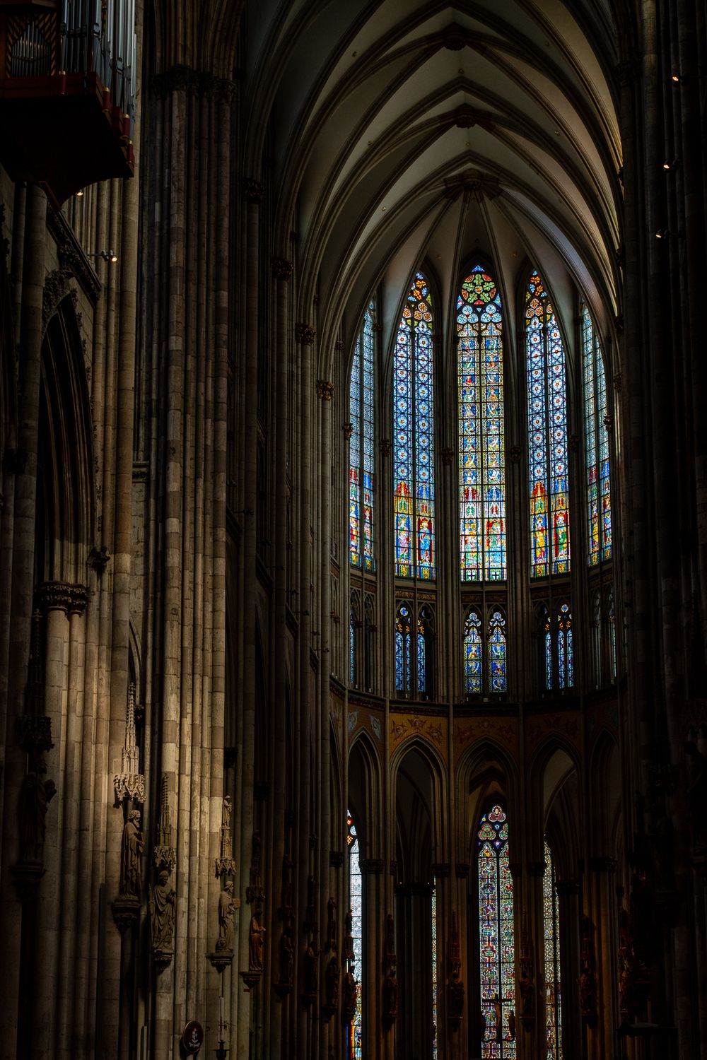 Gothic cathedral interior with soaring arches and colorful stained glass windows.