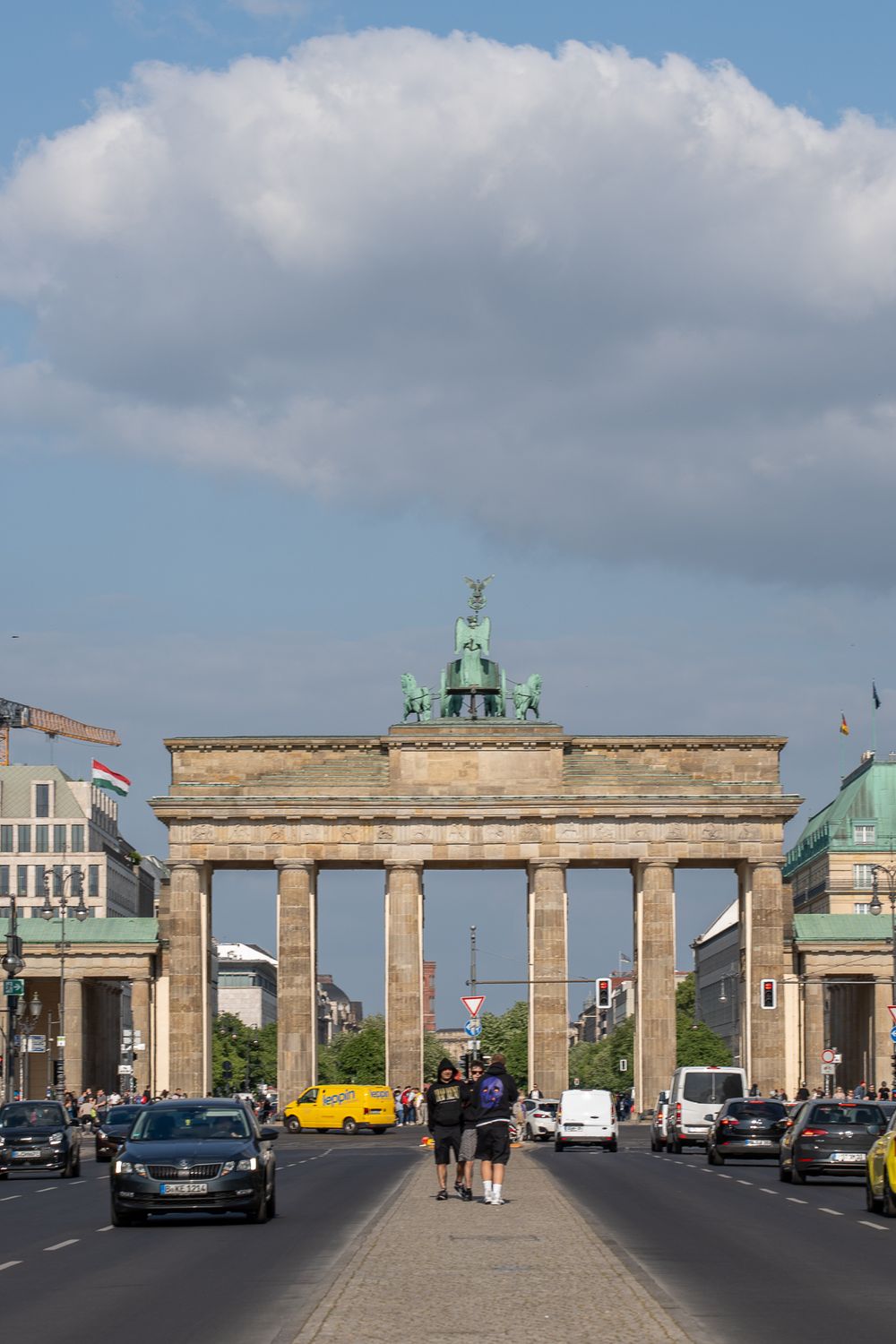 Brandenburg Gate in Berlin with cloudy sky and traffic.