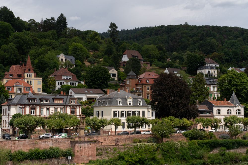 Colorful hillside houses overlook a scenic European riverside town with traditional architecture.