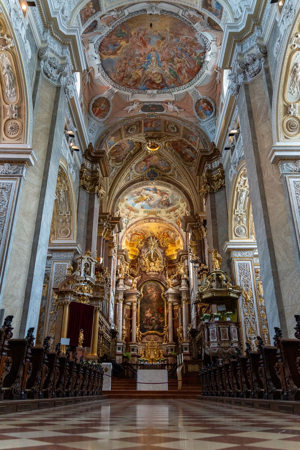 Ornate baroque church interior with painted ceiling frescoes and gilded altar.