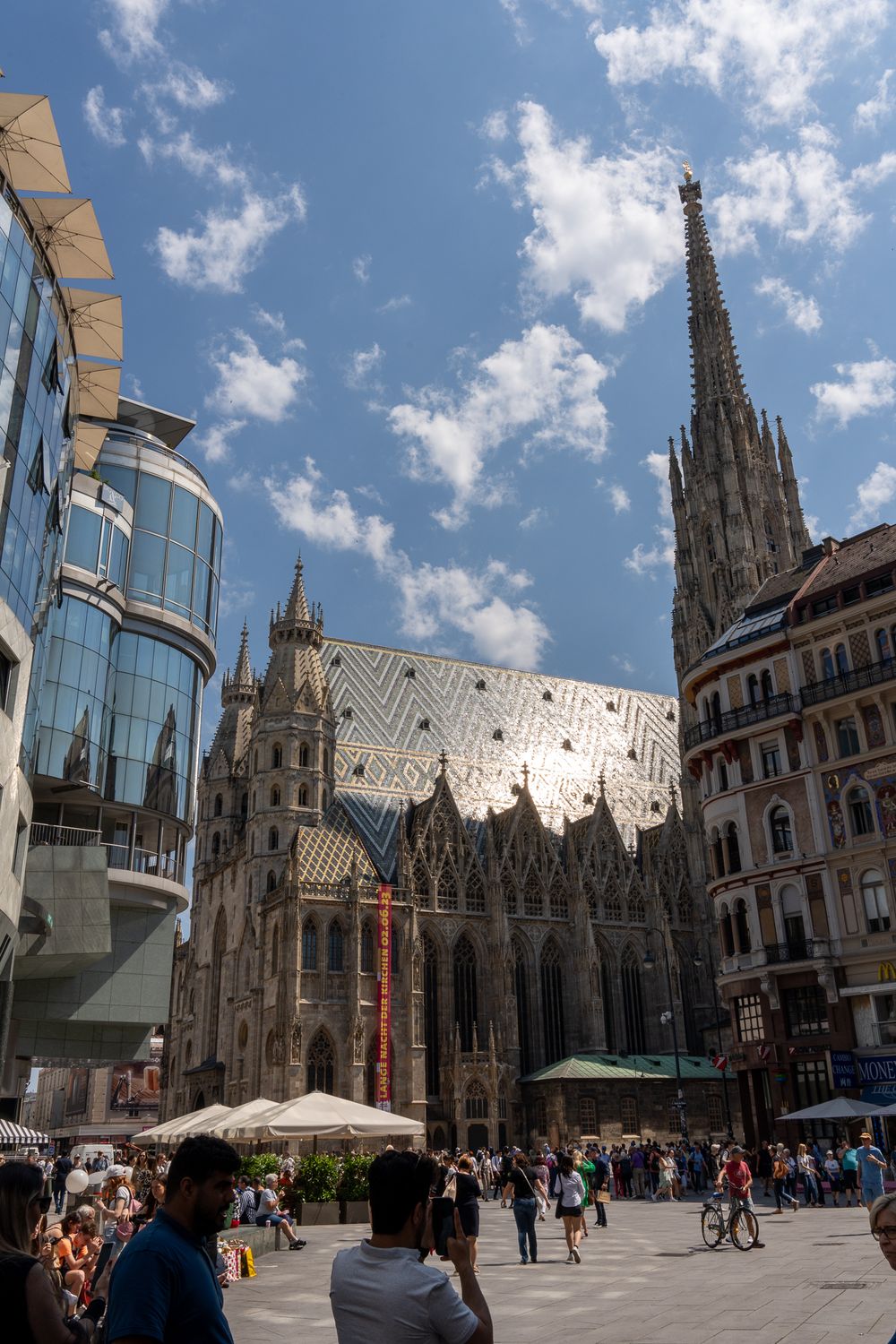St. Stephen's Cathedral in Vienna showcases Gothic architecture against modern buildings and blue sky.