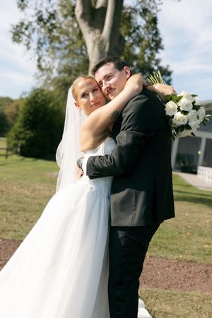 Husband and wife embracing each other in sunlight.
