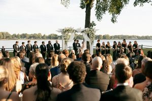 Wedding guests seated in rows watching outdoor ceremony by the water.
