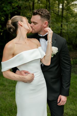Newlywed couple sharing intimate kisses in a garden setting with bride in off-shoulder dress.