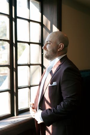 Groom looking out the window and smiling