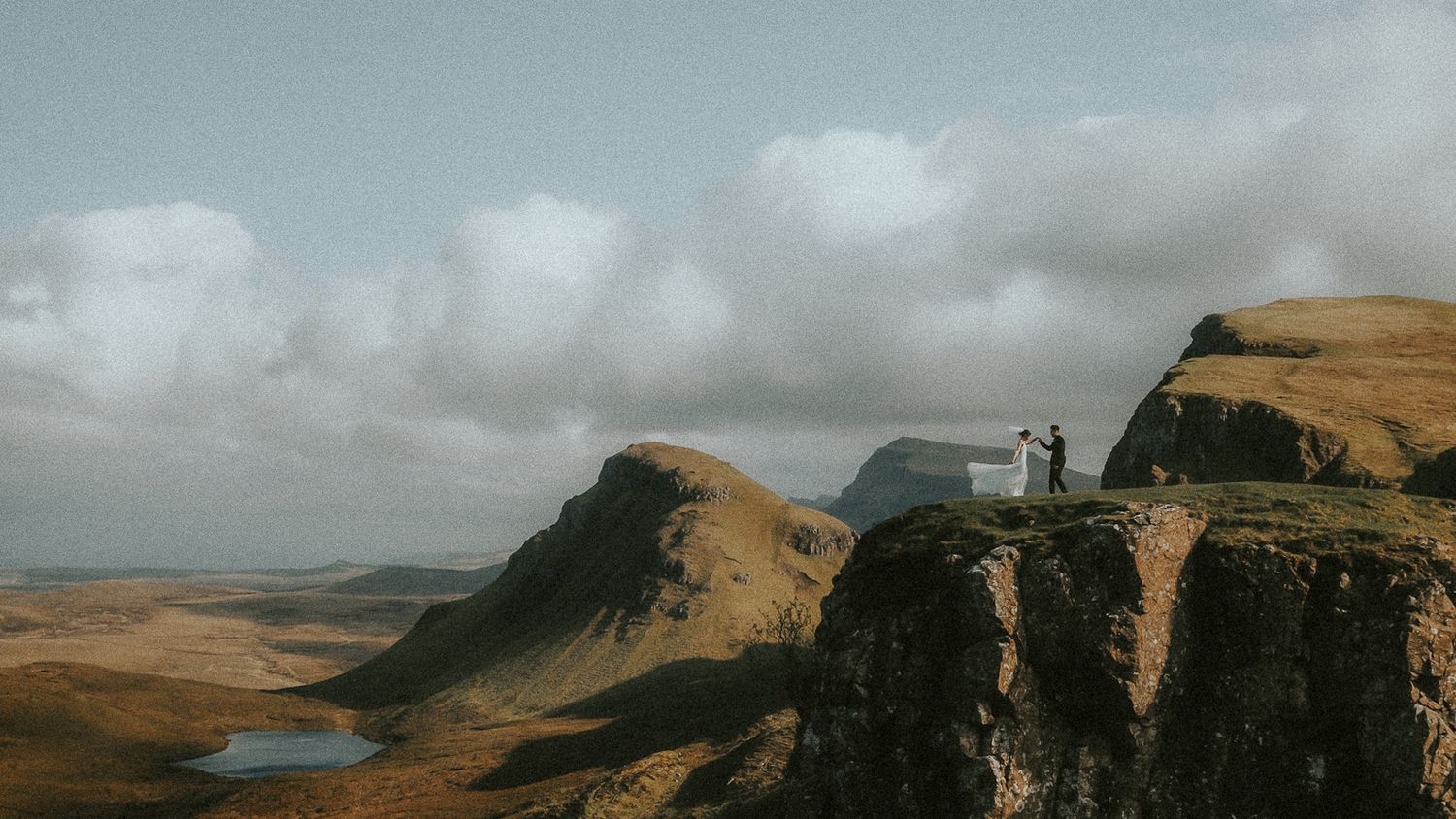 Dramatic landscape photograph of the Quiraing, Skye; a newlywed couple have their first dance on a cliff top