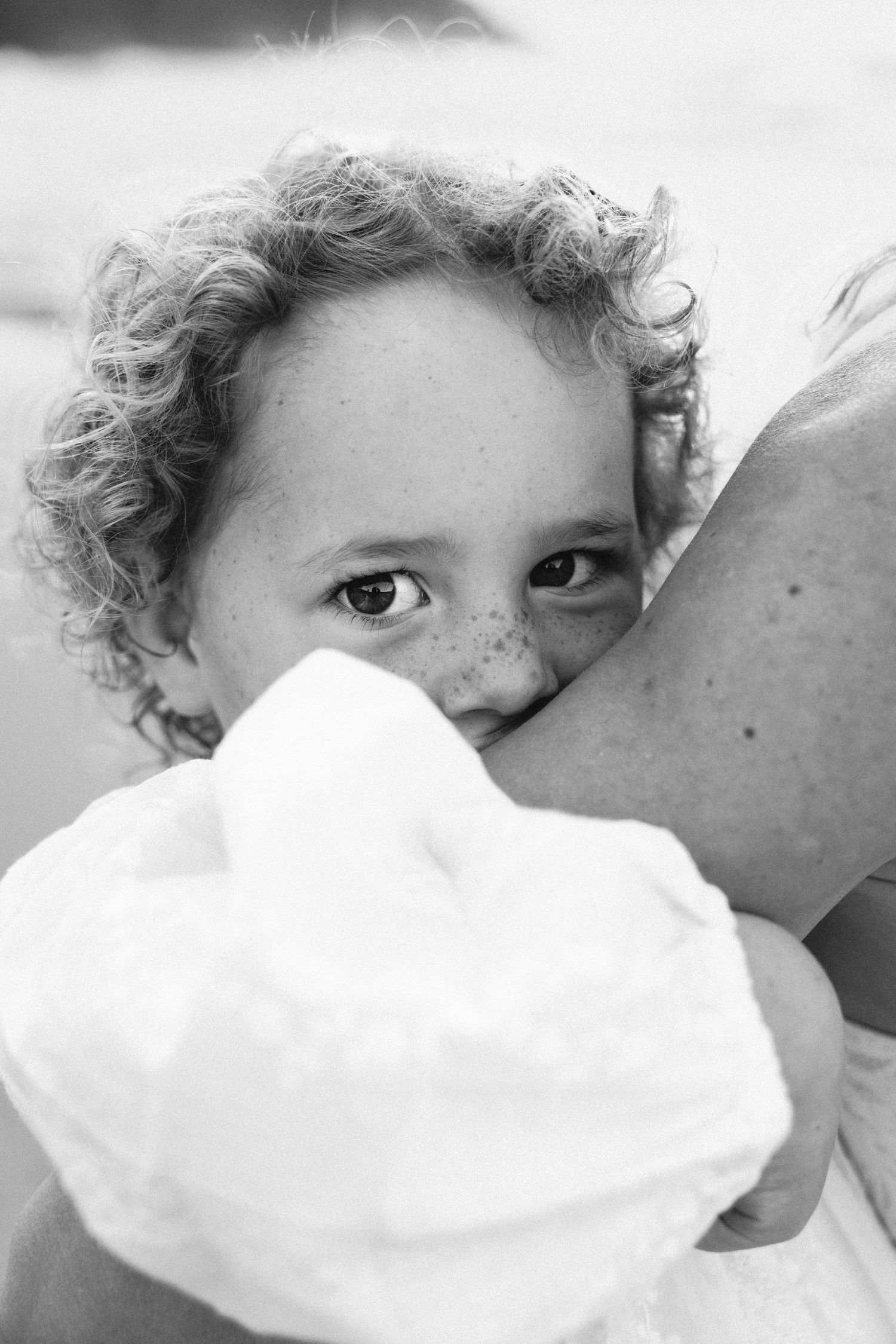 Family Photography - Candid Portrait of Child on Mom's Arm in black and white at Bilgola Beach, Northern Beaches, Sydney