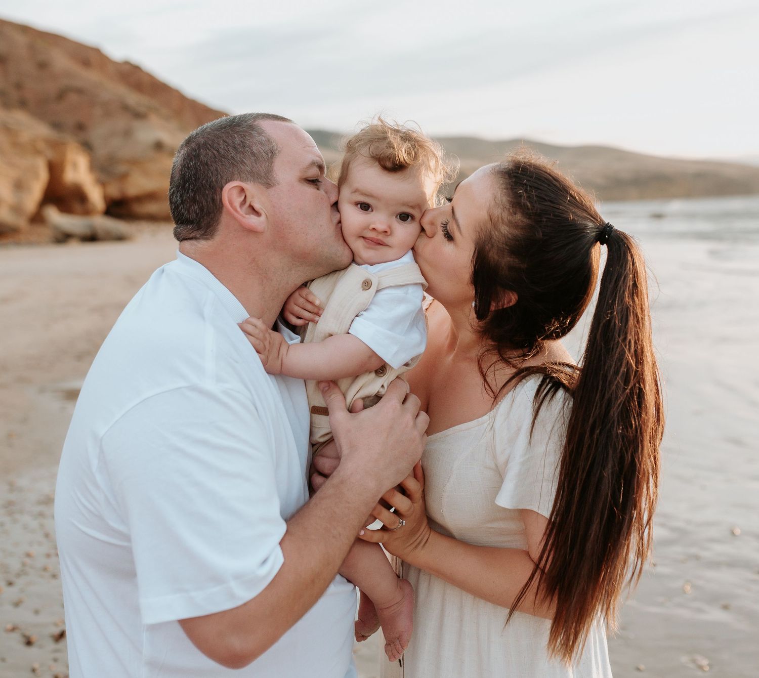 Joyful family beach photoshoot sequence with white outfits against coastal backdrop.