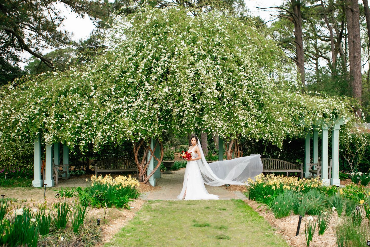 Garden wedding venue with white pillars and green archways creating a romantic outdoor setting.
