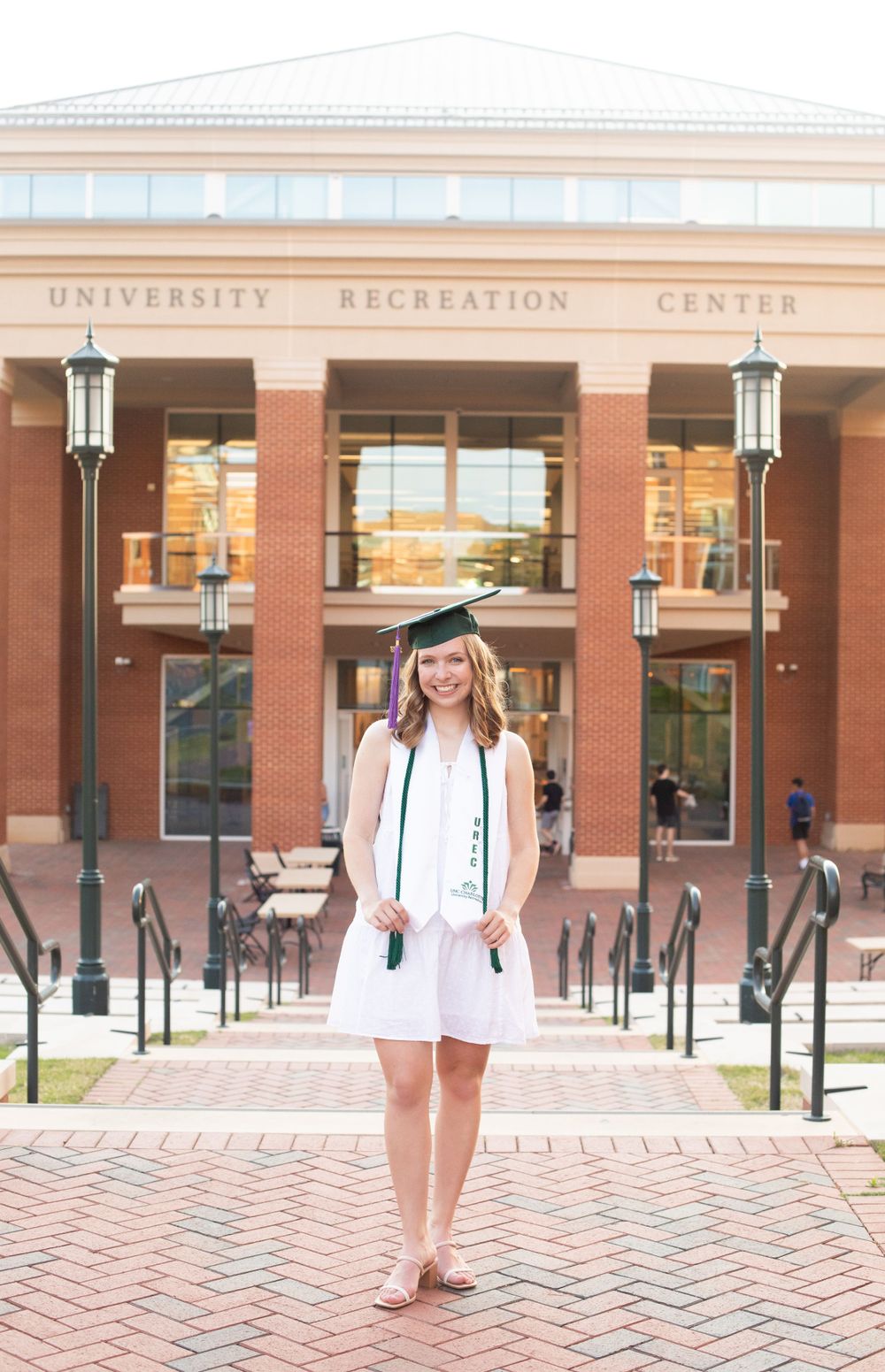 Graduate poses in front of UNC Charlotte Recreation Center building.