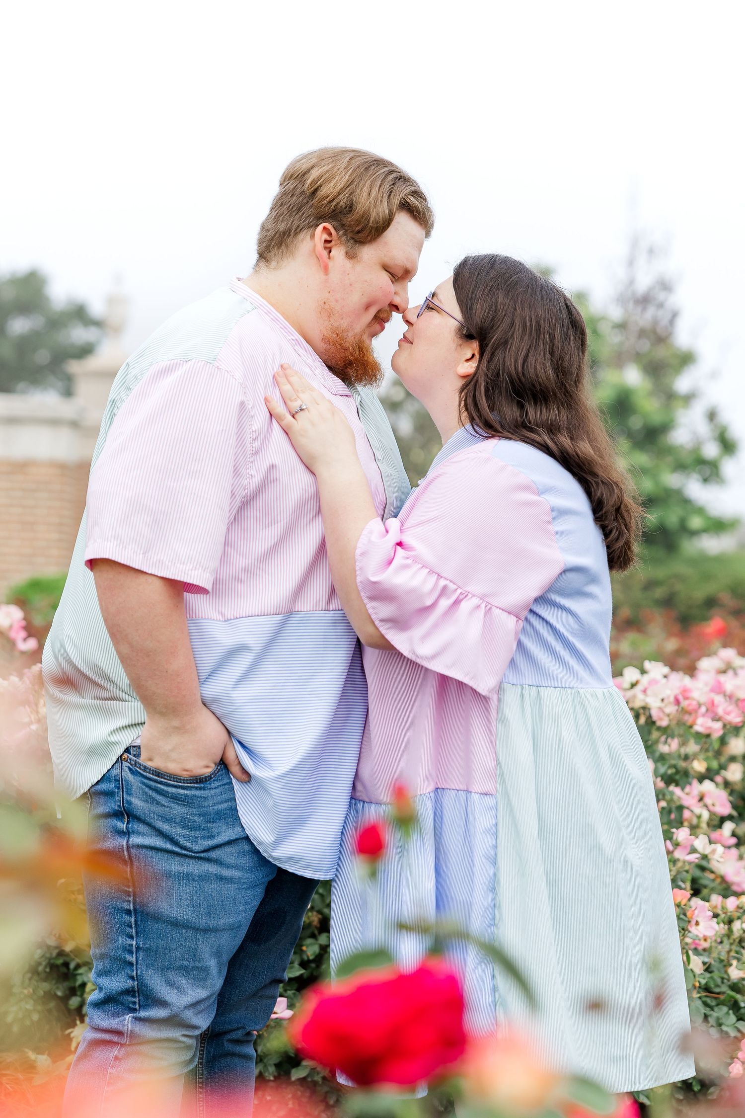 Couple holding each other romantically on a flower field shoeing the engagement ring