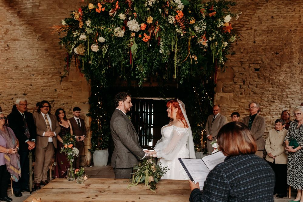 Couples dancing and celebrating at a rustic brick-walled wedding reception venue with hanging floral decorations.