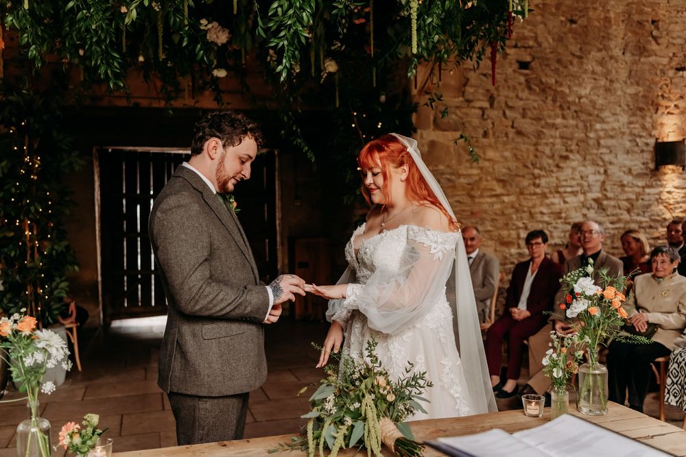 A wedding couple shares an intimate moment during their reception in a rustic brick-walled venue with string lights.