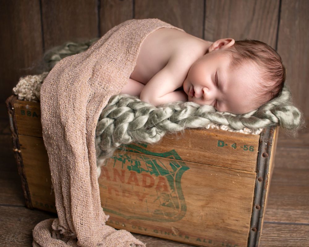 A newborn baby lies sleeping on a vintage soda crate