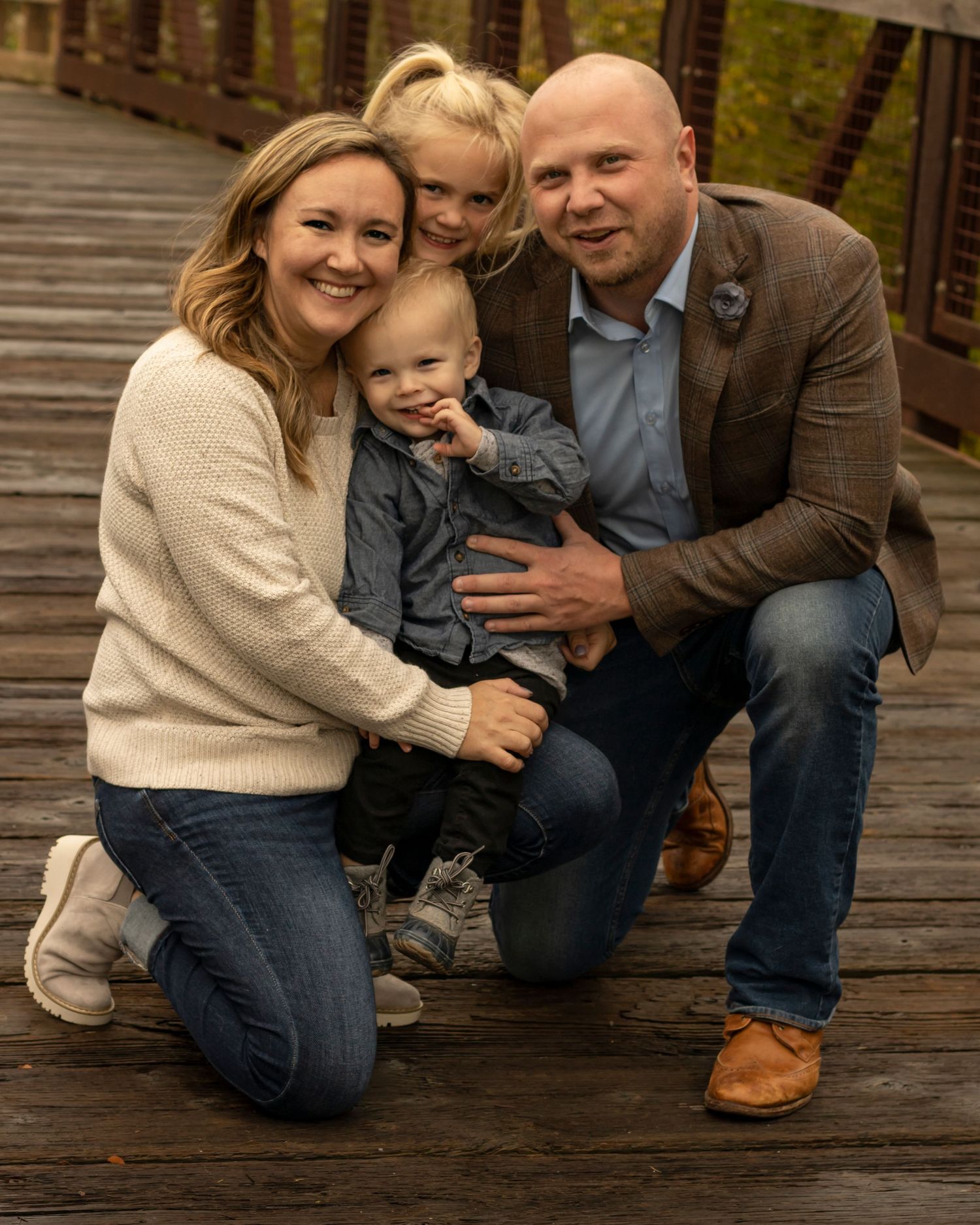 A family of four snuggles closely while outdoors
