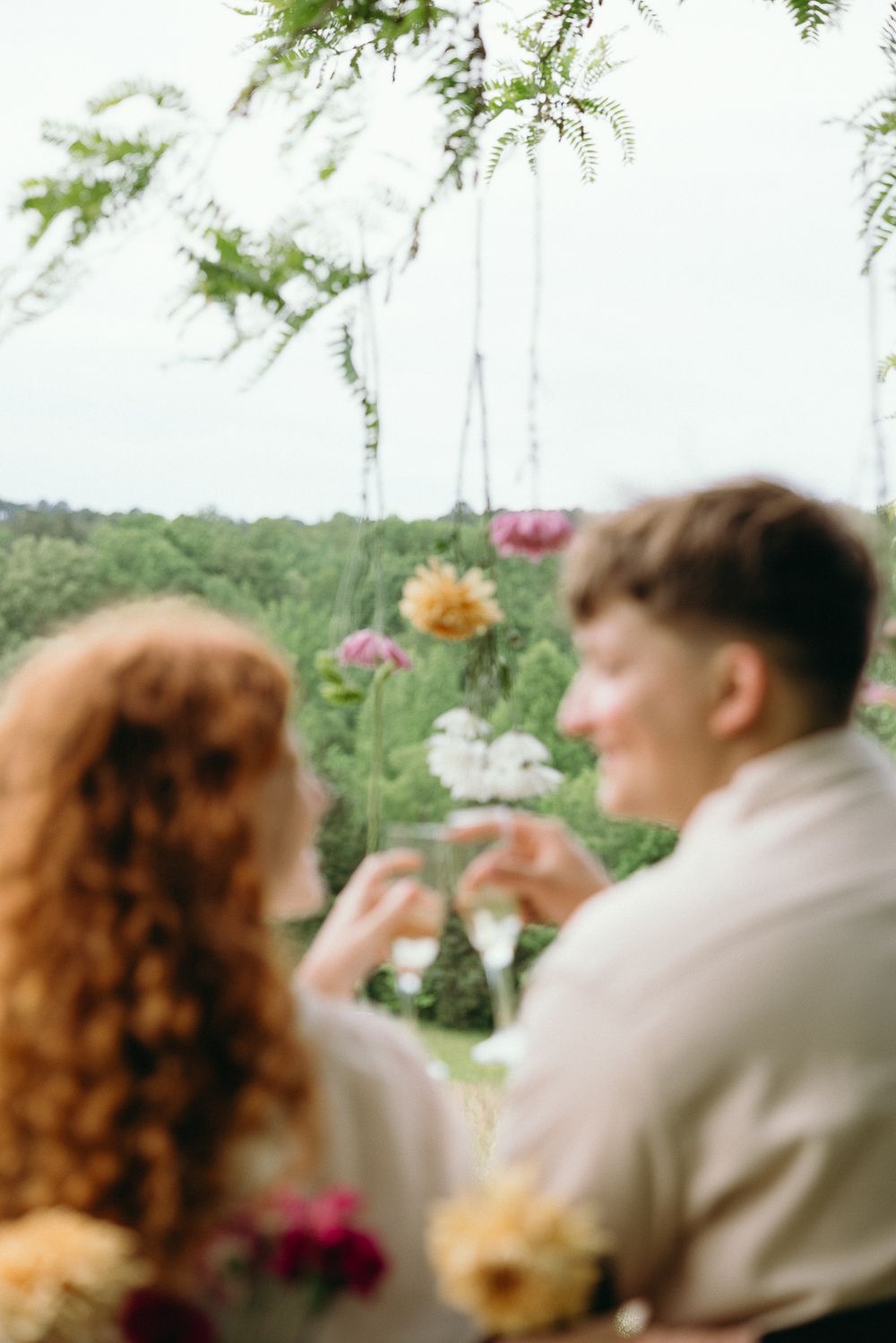 Hanging floral decorations frame a romantic outdoor scene. Le Château du Cœur Wedding Photographer