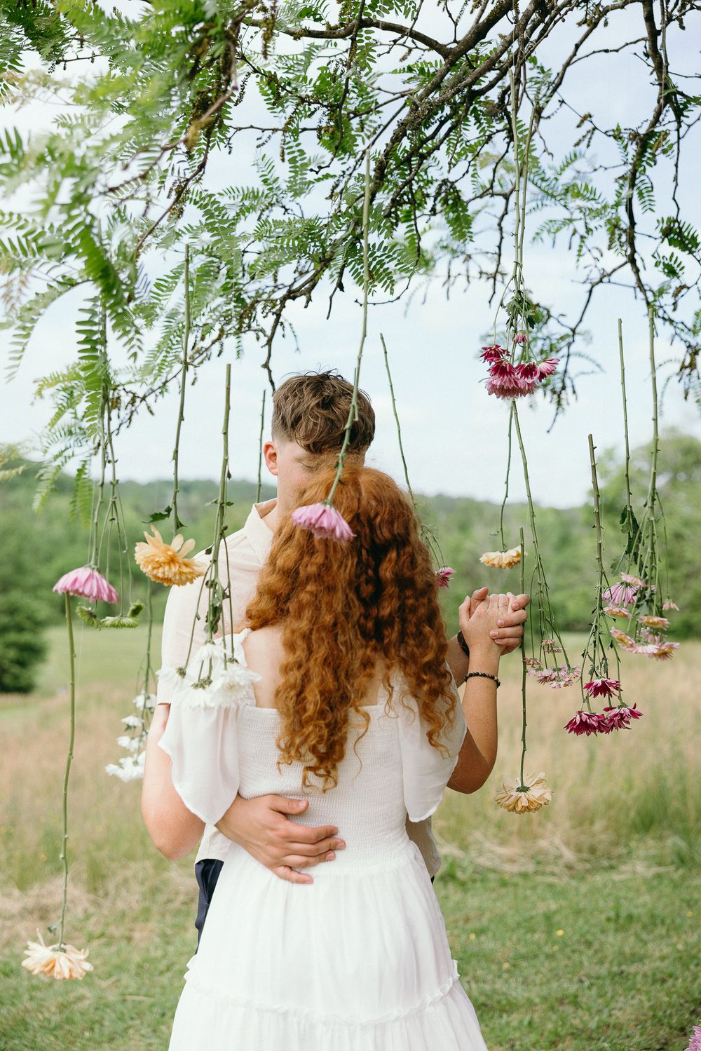 Suspended flowers create a romantic backdrop for an intimate outdoor moment. Le Château du Cœur Wedding Photographer