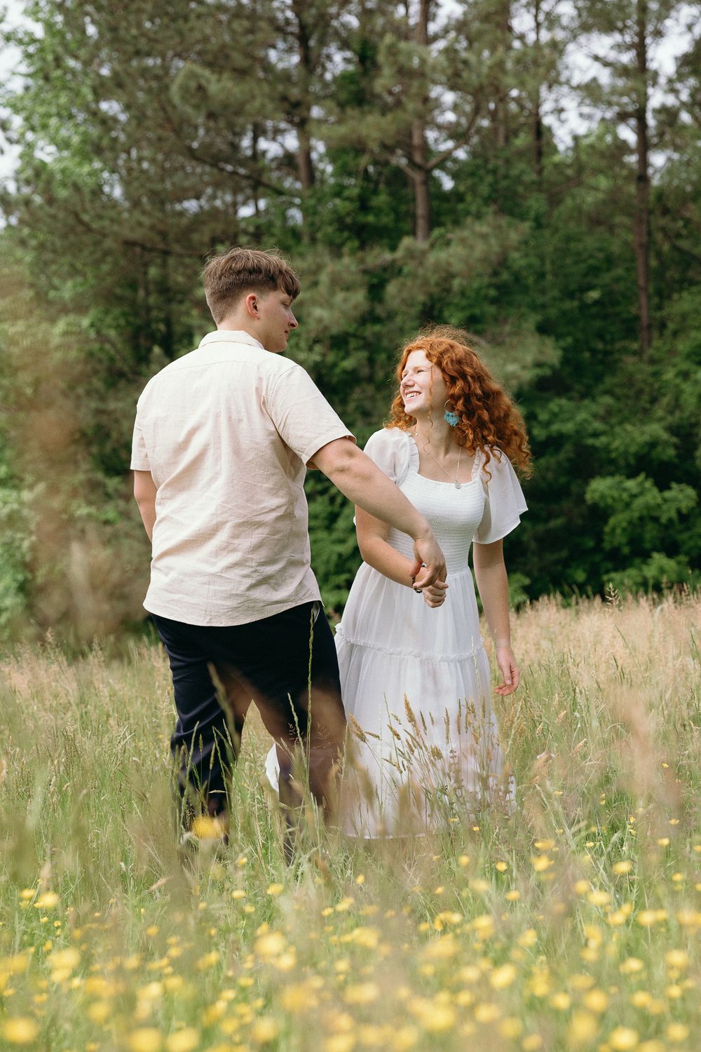 A couple dances playfully through a wildflower field on a summer day. Le Château du Cœur Wedding Photographer