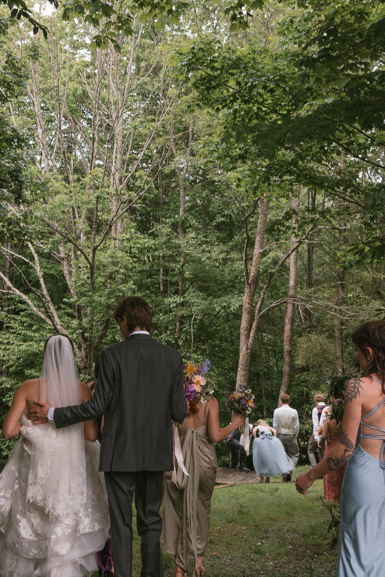 Wedding party walking through a lush green forest path. Luxury wedding photographer North Carolina
