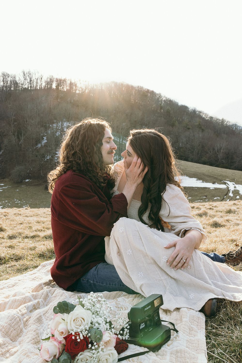 A romantic picnic scene on a hillside with flowers and vintage camera. Linbrook Heritage Estate Wedding Photographer