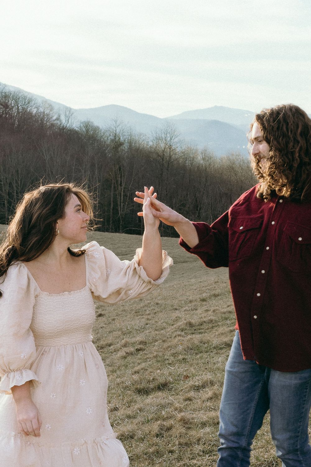 A playful dance moment captured in a mountain field with rolling hills in the background. Twickenham House Wedding Photographer