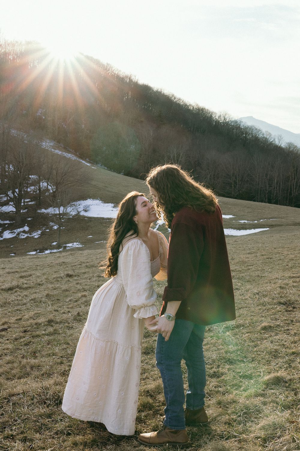 A joyful dance scene unfolds in a mountain meadow at sunset with snow patches visible. Twickenham House Wedding Photographer