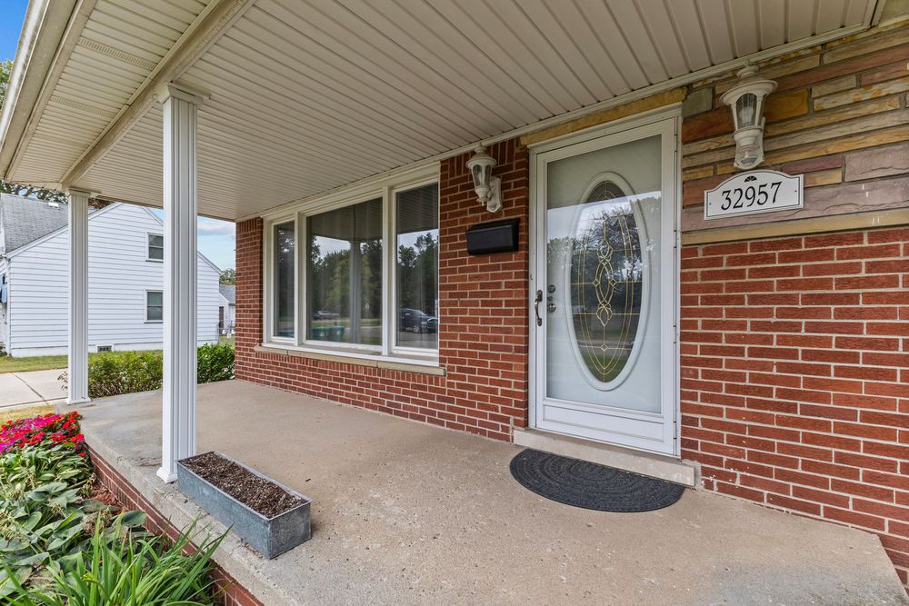 Close-up of brick home entrance with white front door, address number 32057, and covered porch.