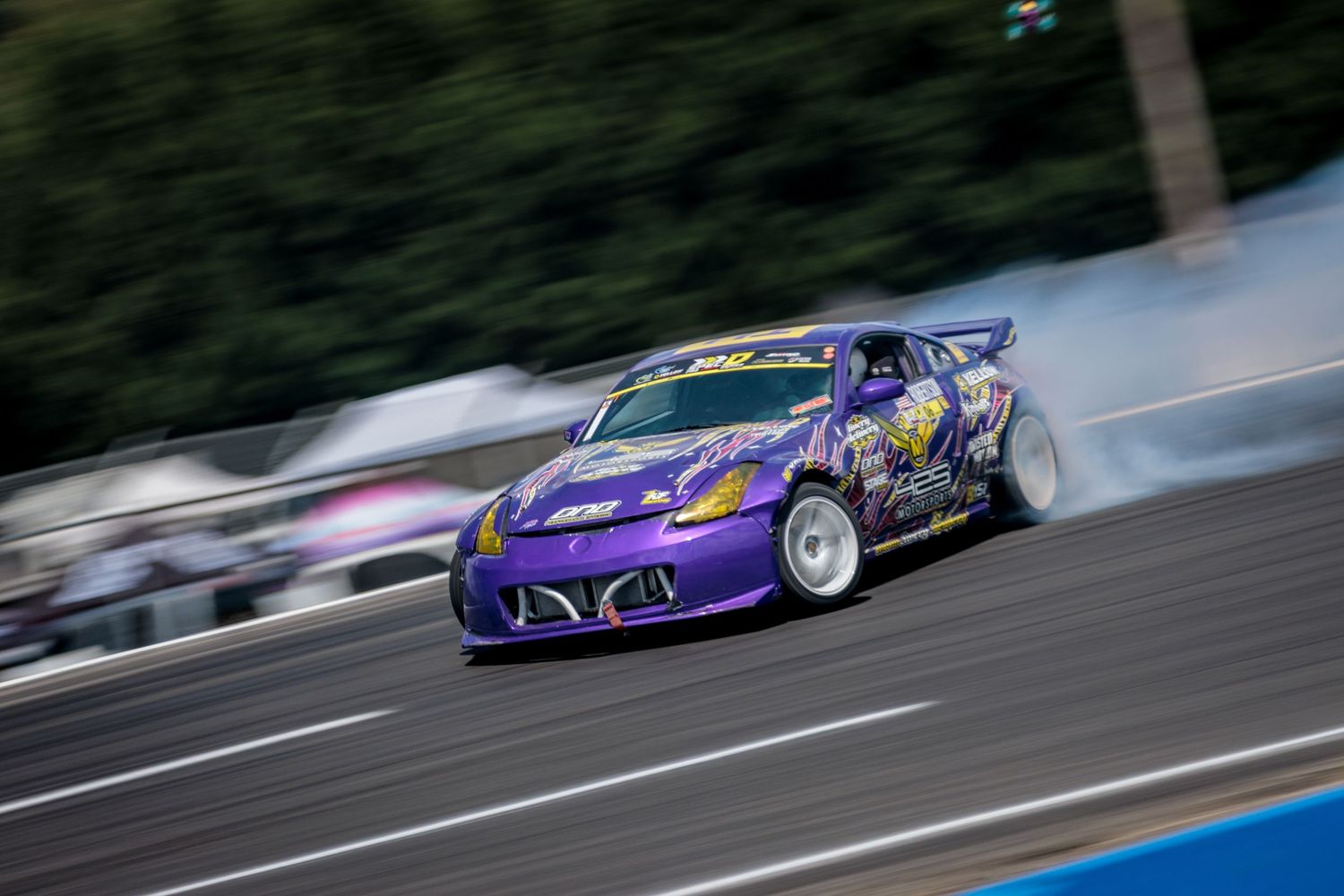 Purple drift car sliding sideways on race track with motion blur effect.