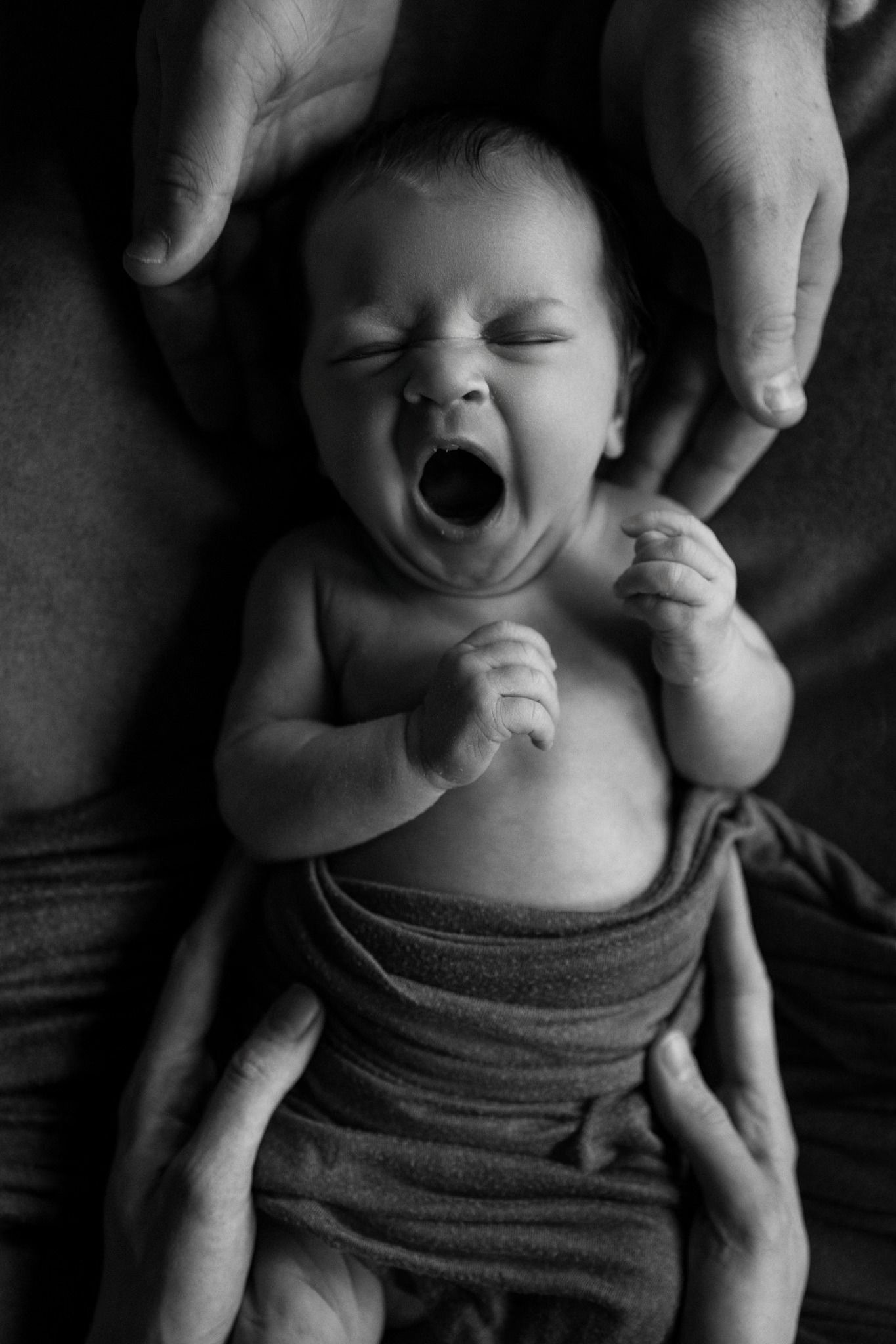 Two mothers holding their newborn baby in a quiet, intimate moment