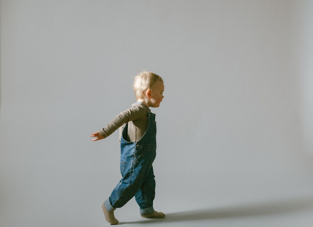 Small child walking across a minimalist white room with natural lighting.
