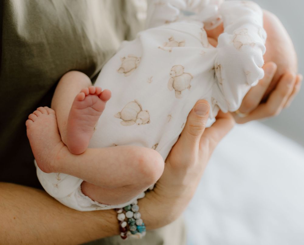 Close-up shots of tiny baby feet wrapped in white patterned fabric.