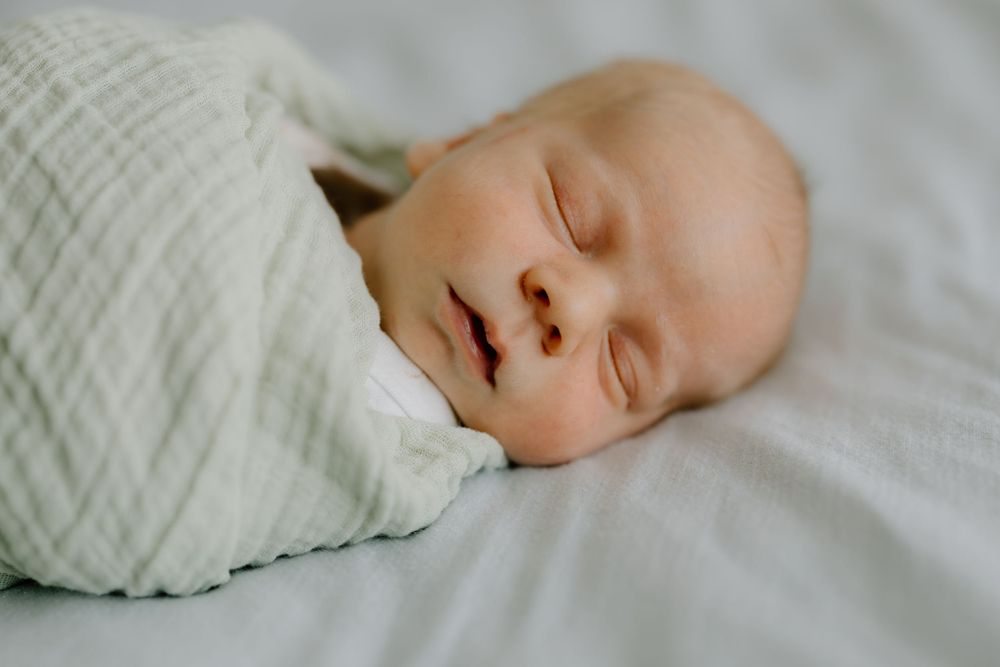 Peaceful newborn baby sleeping soundly on soft white bedding.